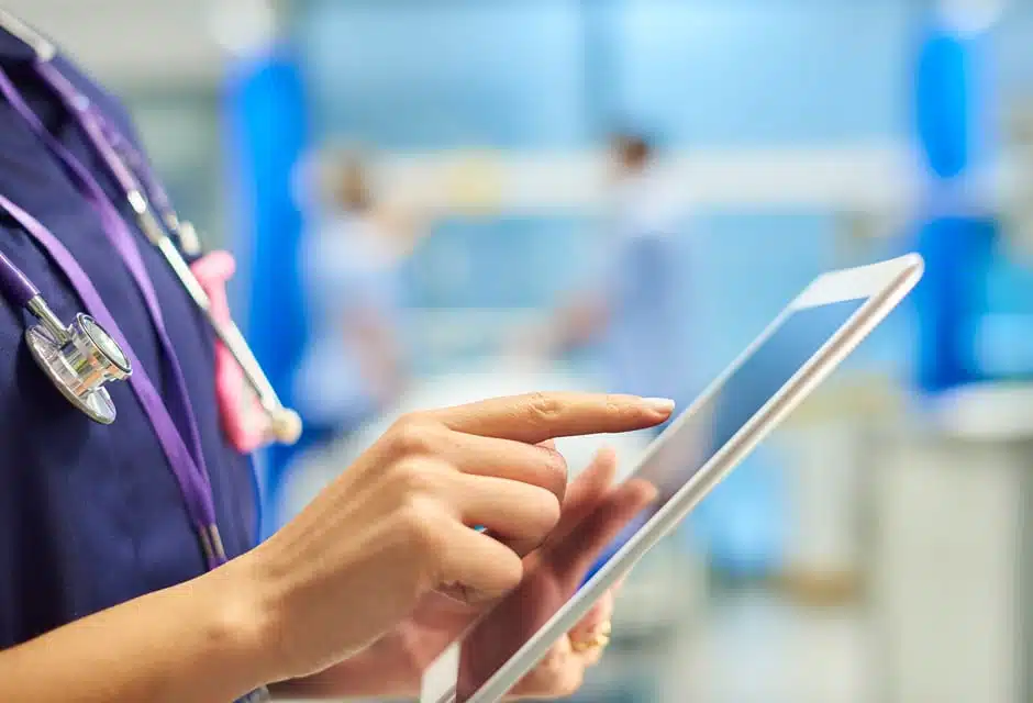 AC-IT-Secteurs-Sante-wifi-et-internet Infirmière utilisant une tablette connectée dans un couloir d'hôpital