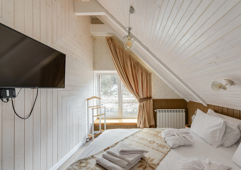 Smart TV accroché au mur d'une chambre d'hôtel aux tons blancs